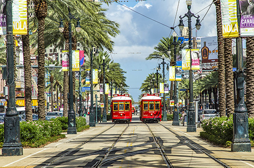 Street in New Orleans with red trollies and palm trees