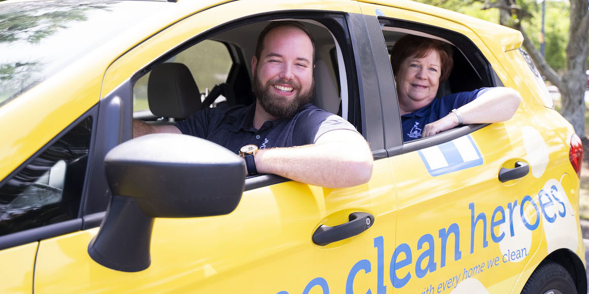 Mother and son franchise owners in a Home Clean Heroes vehicle smiling